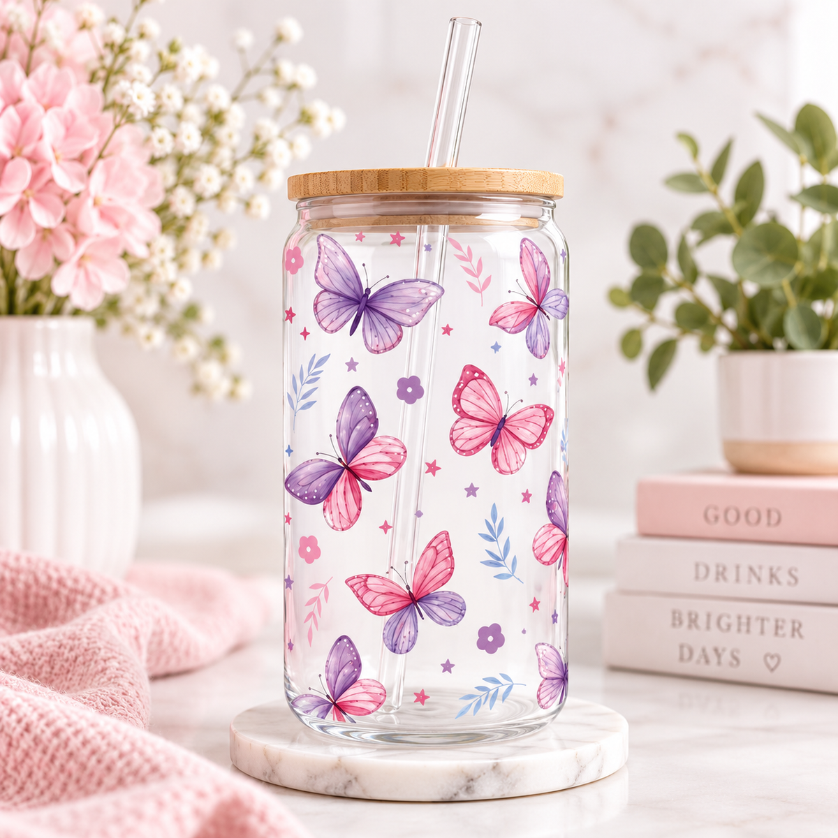 Butterfly glass can with bamboo lid and straw in a pastel floral setting