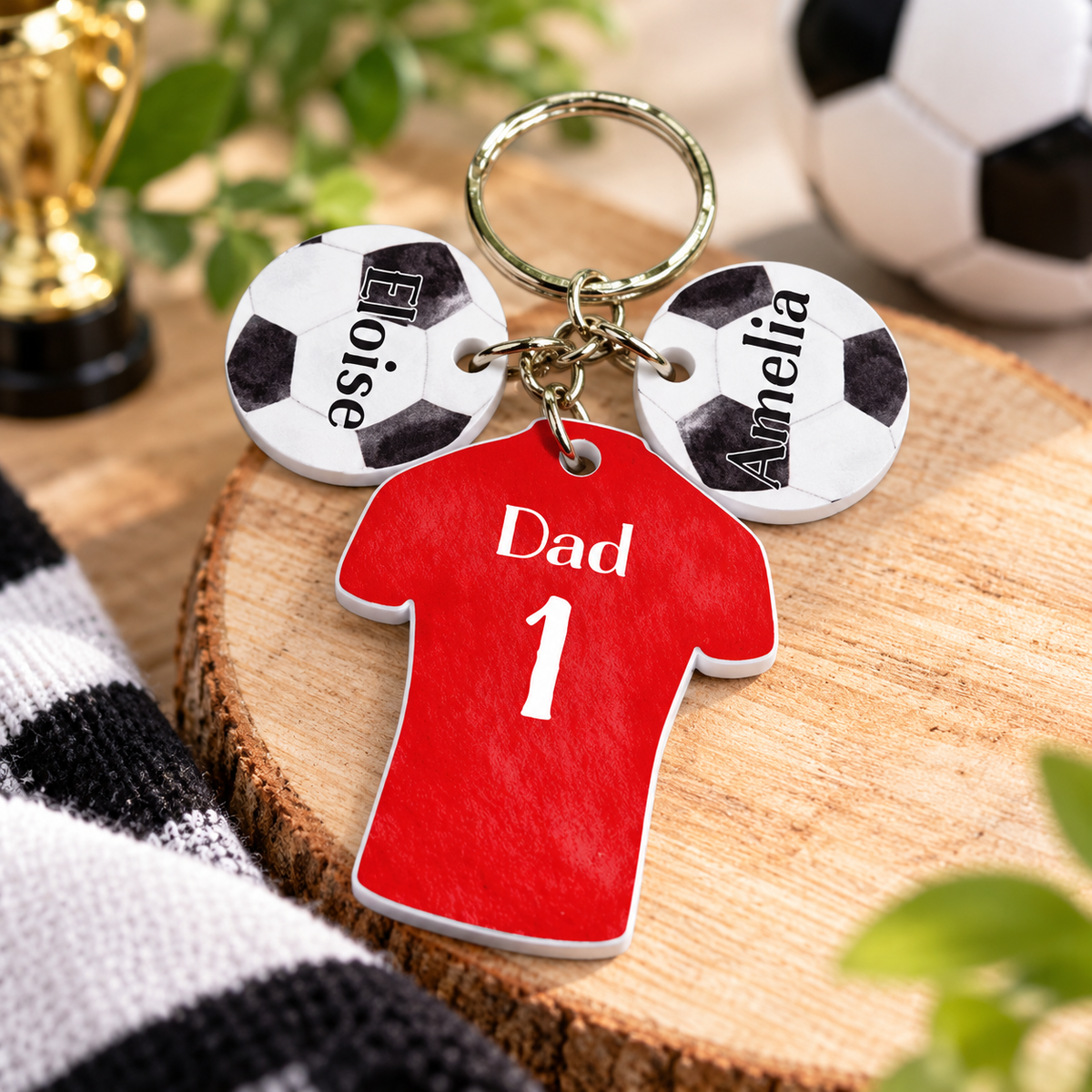 Personalised red football shirt keyring with Dad 1 and two named football charms in a styled football setting